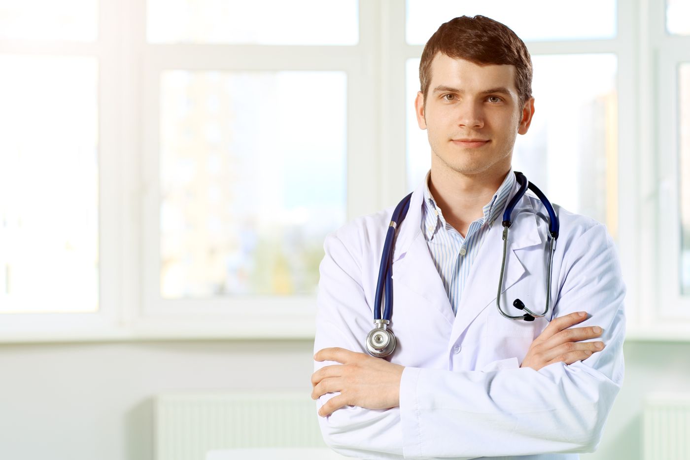 Doctor in a white coat with a stethoscope, arms folded