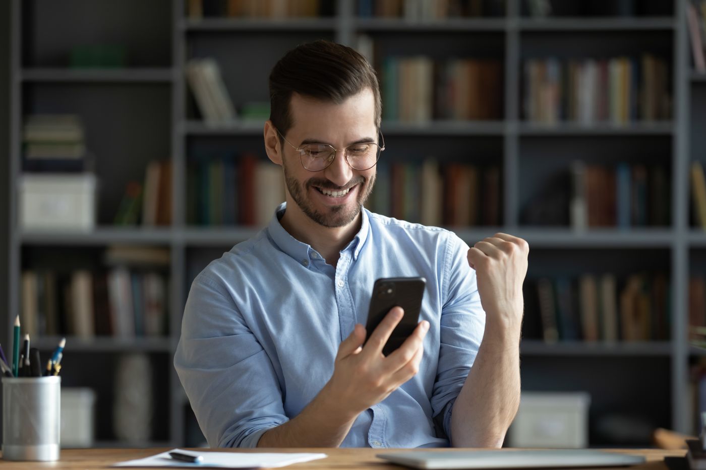 Man at his desk checking a result on his phone