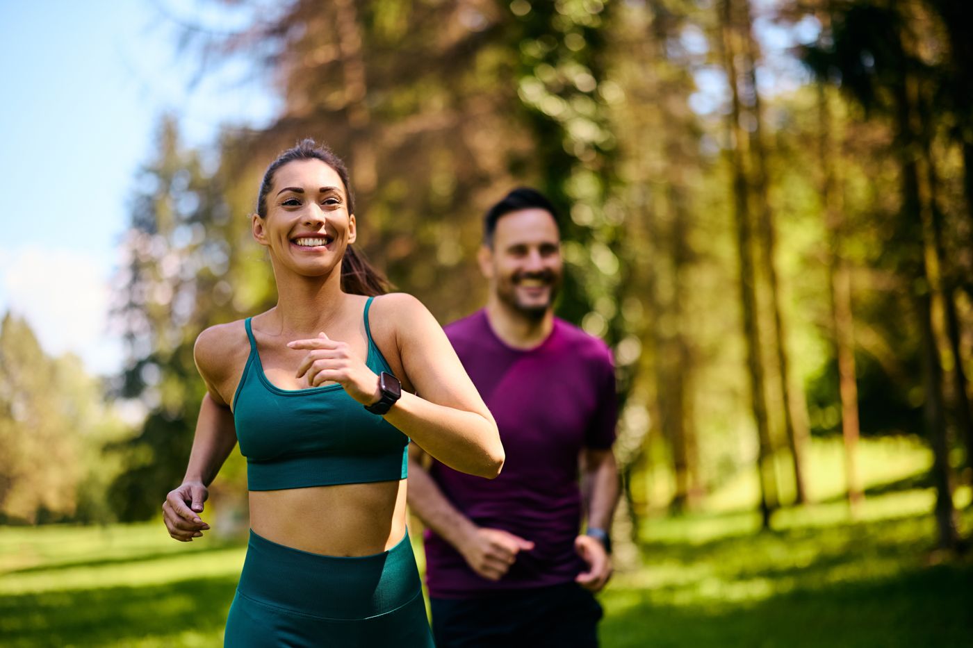 Smiling couple jogging together through a sunny park