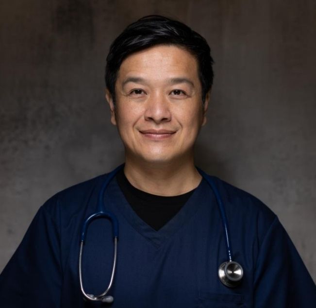 Dr Chun Tang in navy scrubs with a stethoscope