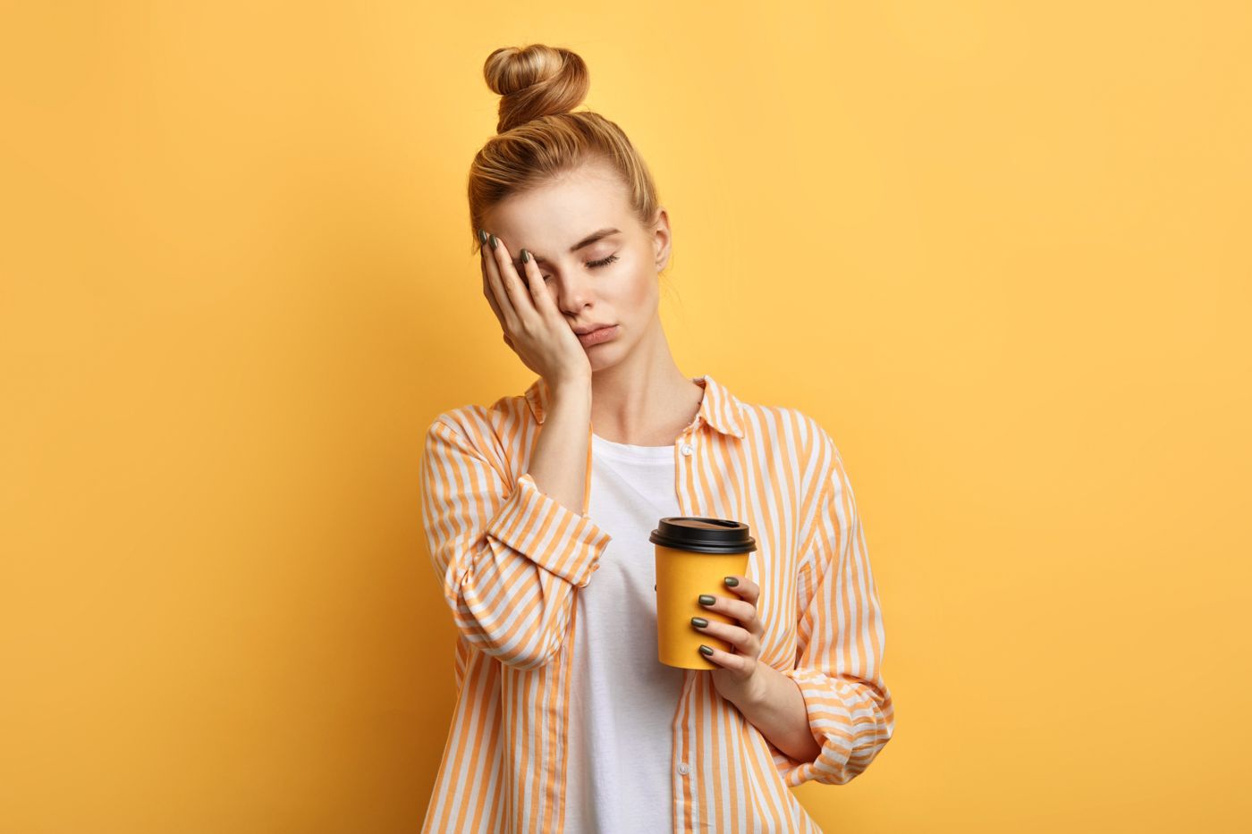 Tired woman holding her face and a coffee cup